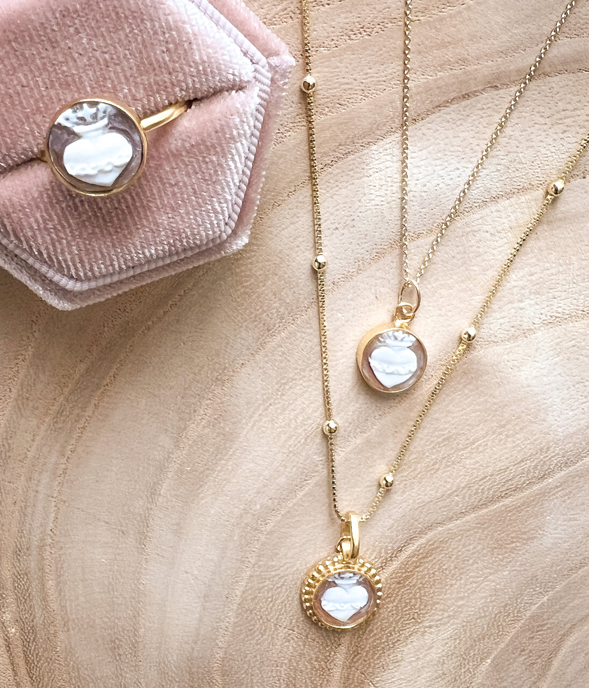 Gold jewelry set featuring a heart-shaped pendant necklace and a matching heart ring, pink velvet ring box.